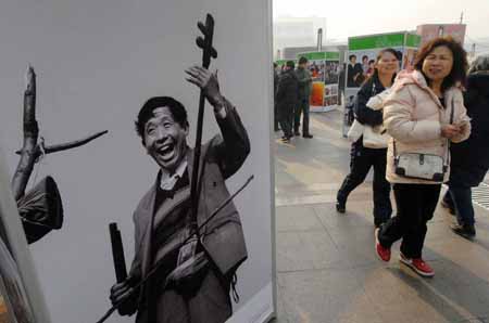 People walk past an old photo at an exhibition featuring China's 30 years' reform and opening-up at Wangfujing Street in Beijing, capital of China, on Dec. 16, 2008. The photo exhibition presenting near 800 pictures in memory of the past 30 years' development was unveiled here on Tuesday.